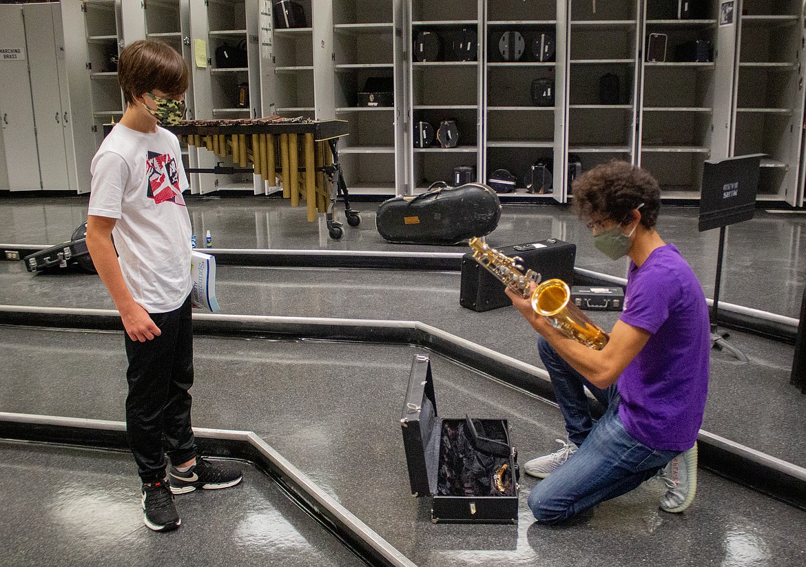 Moses Lake High School Band teacher Pablo Hernandez examines an instrument before handing off to freshman Brandon Harwood on Wednesday, Sept. 16.