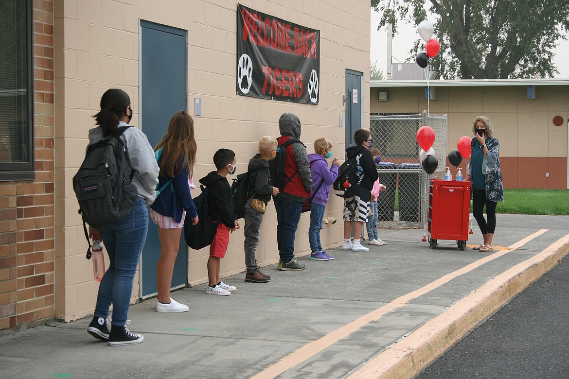 Students at Garden Heights Elementary in Moses Lake listen to instructions on answering health questions before they go to class on the first day of in-person school Thursday.