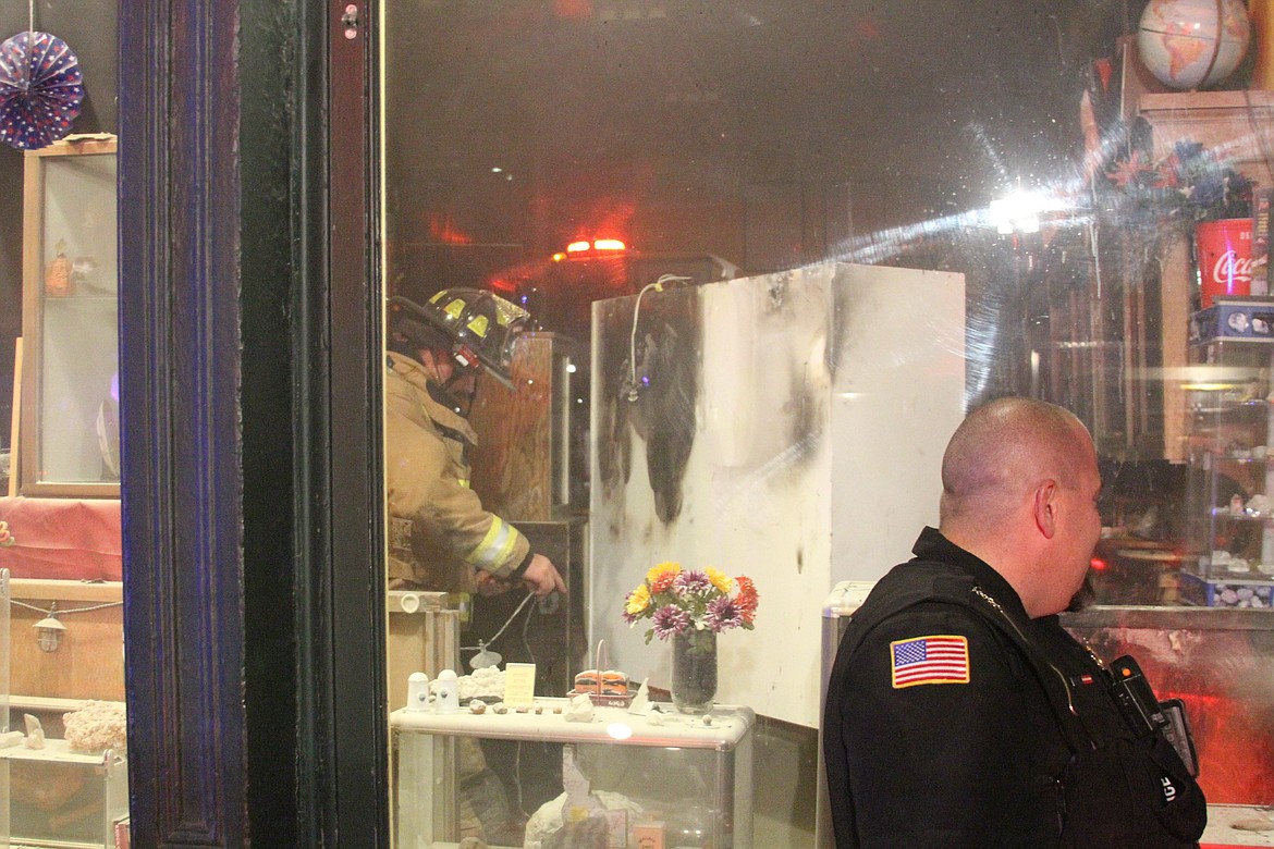 Fire crews work around the area where the fire began inside Johnson's Gems. You can see the scorch marks on the back of the shelf inside the building.