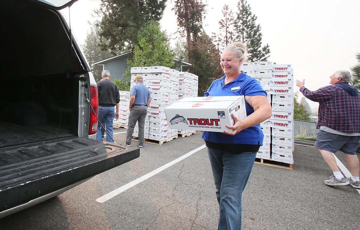 Lake City Center director Marlys Silva helps load a guest's vehicle with a produce package in the parking lot of the center Thursday morning.
