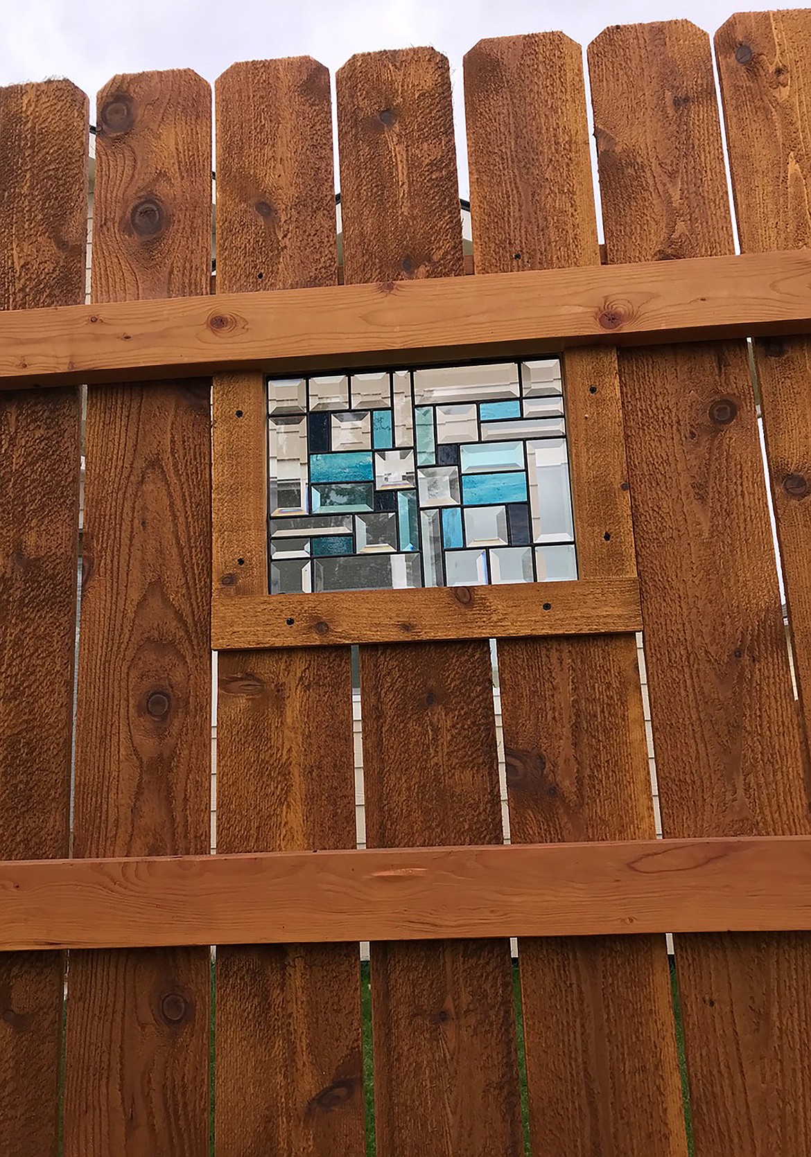 A close-up view of a fence on northwestern side of Sandpoint that features stained glass panels.