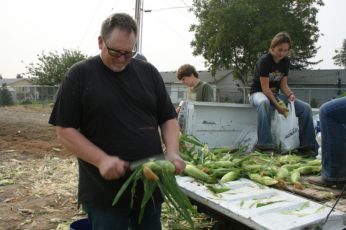 Moses Lake High School FFA advisor Erik Nielsen lops the end off an ear of corn with one good whack. Corn fresh from the field is being sold as a fundraiser for club activities.
