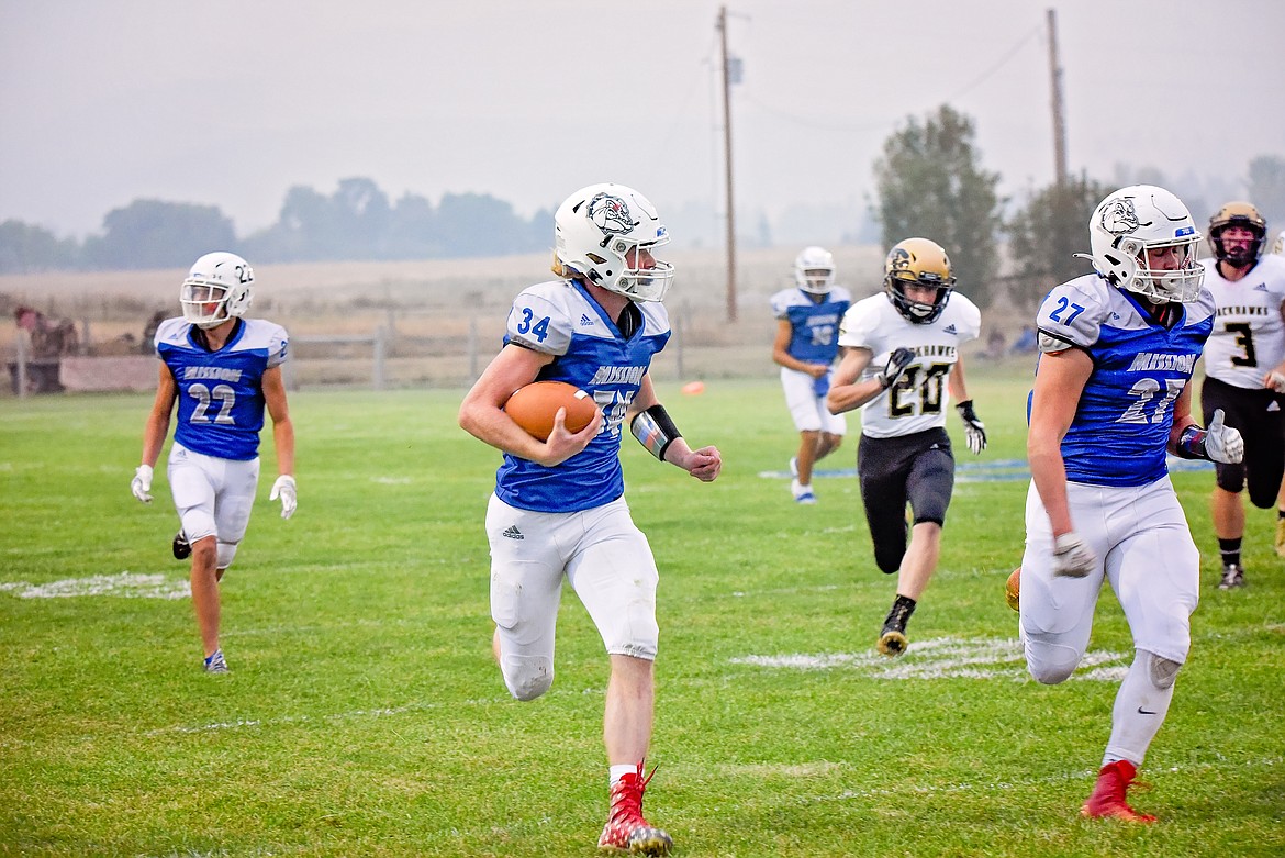 Layne Spindel (34) gets an escort from teammate Ian Killorios (22) trails during a big play against Seeley-Swan. (Christa Umphrey)