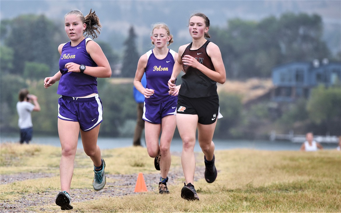 Polson sophomore Karli Owens and junior Halle Heninger run with Ronan sophomore Olivia Heiner as the trio vies for position during a varsity cross country race Saturday at the Polson Fairgrounds.. (Scot Heisel/Lake County Leader)