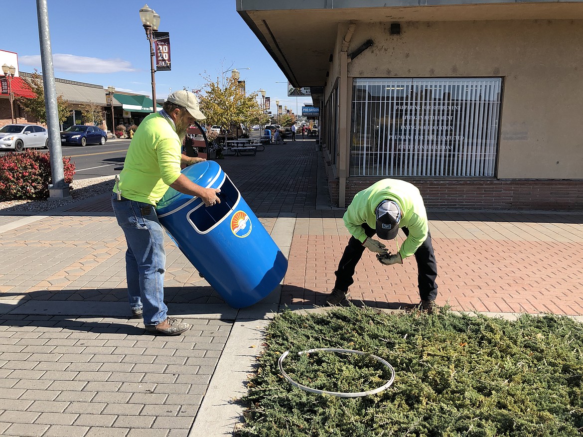 Moses Lake City maintenance workers Lee Willis (left) and Berto Chavez (right) prepare to place a new trash receptacle at the corner of Third Avenue and Ash Street on Thursday.