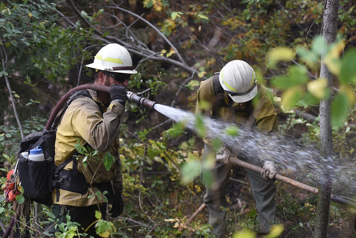 Justin Pilkington mans a hose while Sam Westlin uses a rouge hoe to turn up soil. The Eureka-based firefighters worked along the edge of the smoldering Callahan fire on Sept. 22.