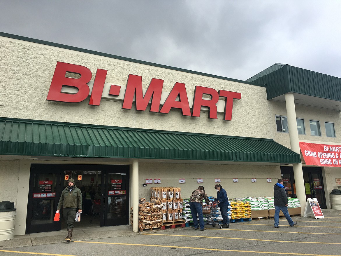 A shopper leaves the Rathdrum Bi-Mart at its grand opening in March, while others look over merchandise in front of the store on Highway 41.