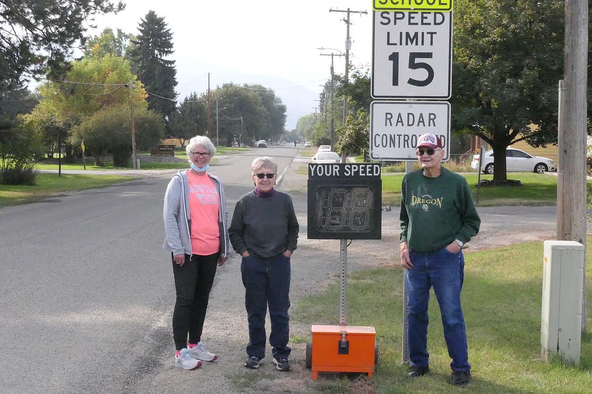 Patti Hanson, left, Shirley Helterline and Dave Helterline display a speed zone sign and newly installed speed indicator board on Clayton Street along the east side of Plains School. The group worked with city officials in an effort to slow speeding drivers in the hope of stopping a tragedy. (Chuck Bandel/Valley Press)