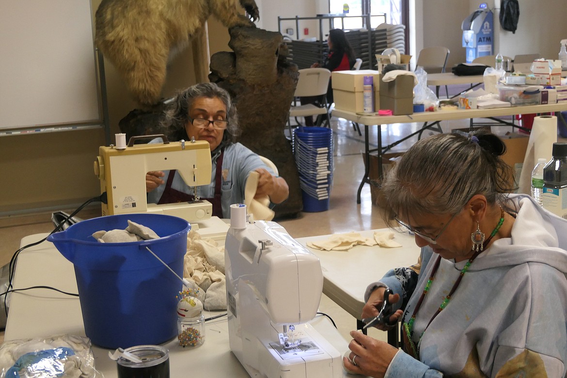 Dorothy Nunez, left, curatorial assistant for the C.M. Russell Museum in Great Falls, led a small cadre of sewing assistants, including Aggie Incashola, People’s Center Education Director, in the construction of small cotton pouches to hold activated charcoal pellets. The charcoal will absorb acids and other contaminants to keep the photos from further degrading while in storage. (Carolyn Hidy/Lake County Leader)