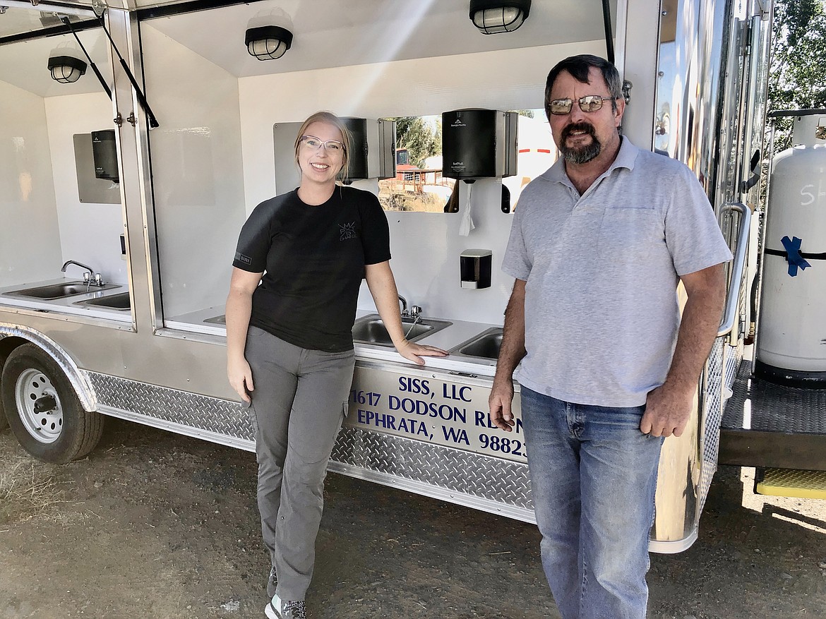 Sarah Schutt and her father Scott pose with one of their portable hand washing stations, which they haul out to wildfires to help give fire crews a chance to clean up.