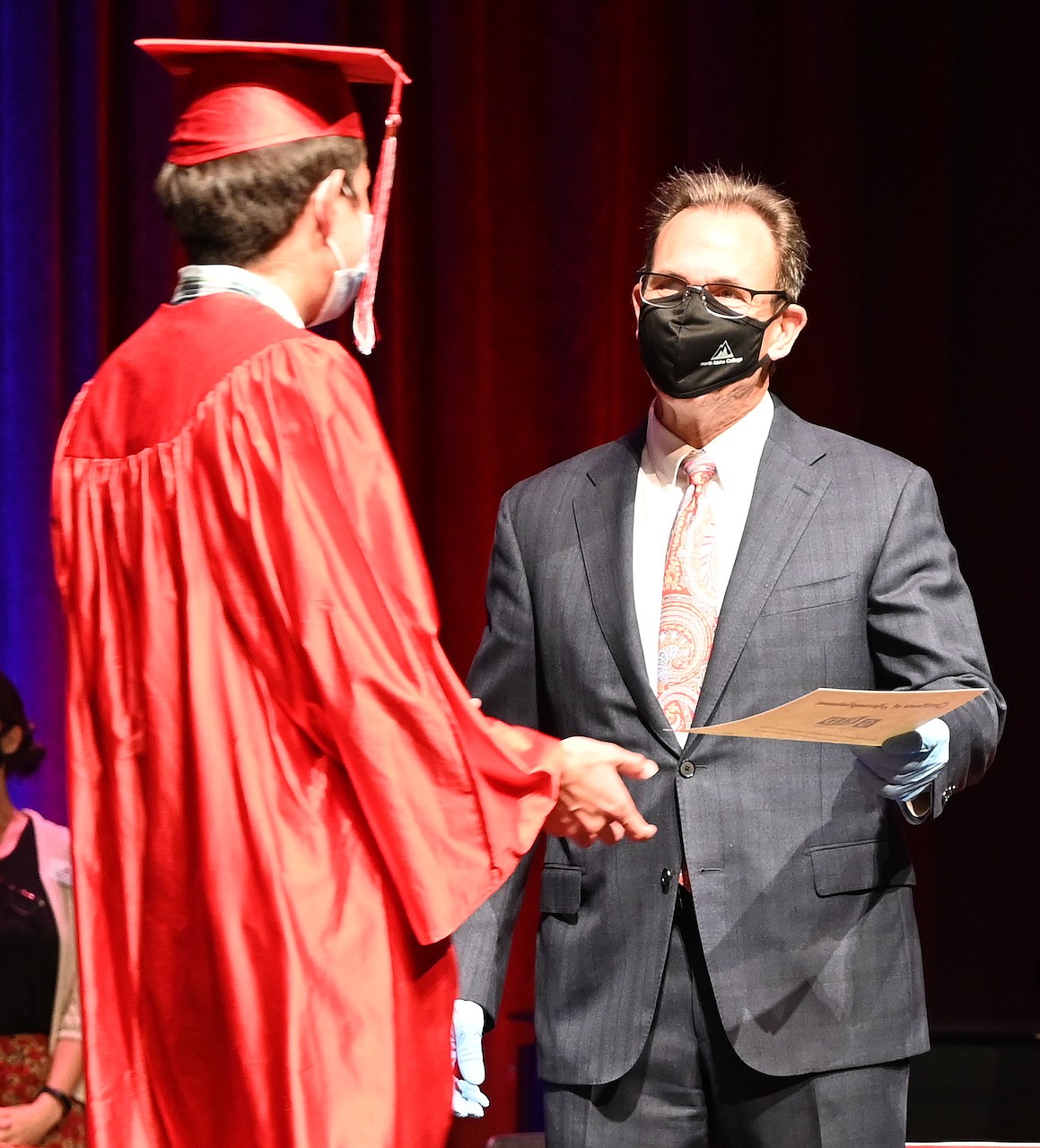 North Idaho College President Rick MacLennan hands a GED diploma to a graduate of the NIC Adult Education Center during a graduation ceremony on Sept. 10.