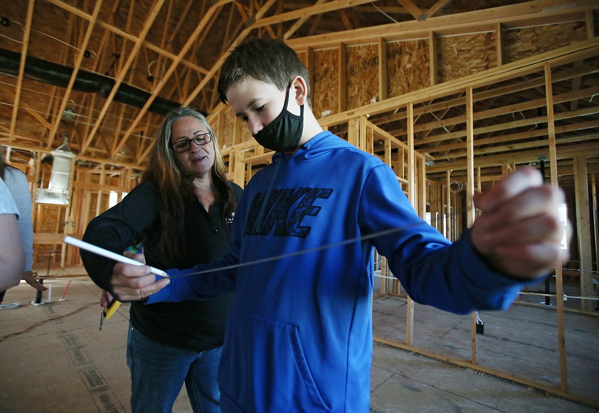 Woodland Middle School eighth-grader Wyatt Hernandez receives a building lesson as Greenstone Homes construction superintendent Shari Hohenberger pencils ticks on a tape measure Tuesday morning. Wyatt and his classmates are learning all about the housing market right now, including how prices are calculated and how new homes are built.