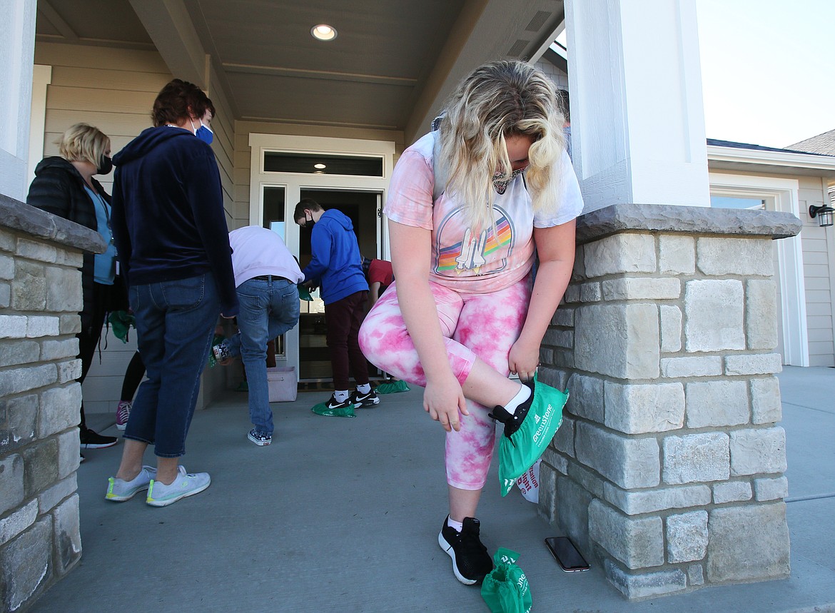 Julia Cosson, Woodland Middle School seventh-grader, slips on booties as she and her classmates go on a tour in a brand new Greenstone Homes house Tuesday morning.