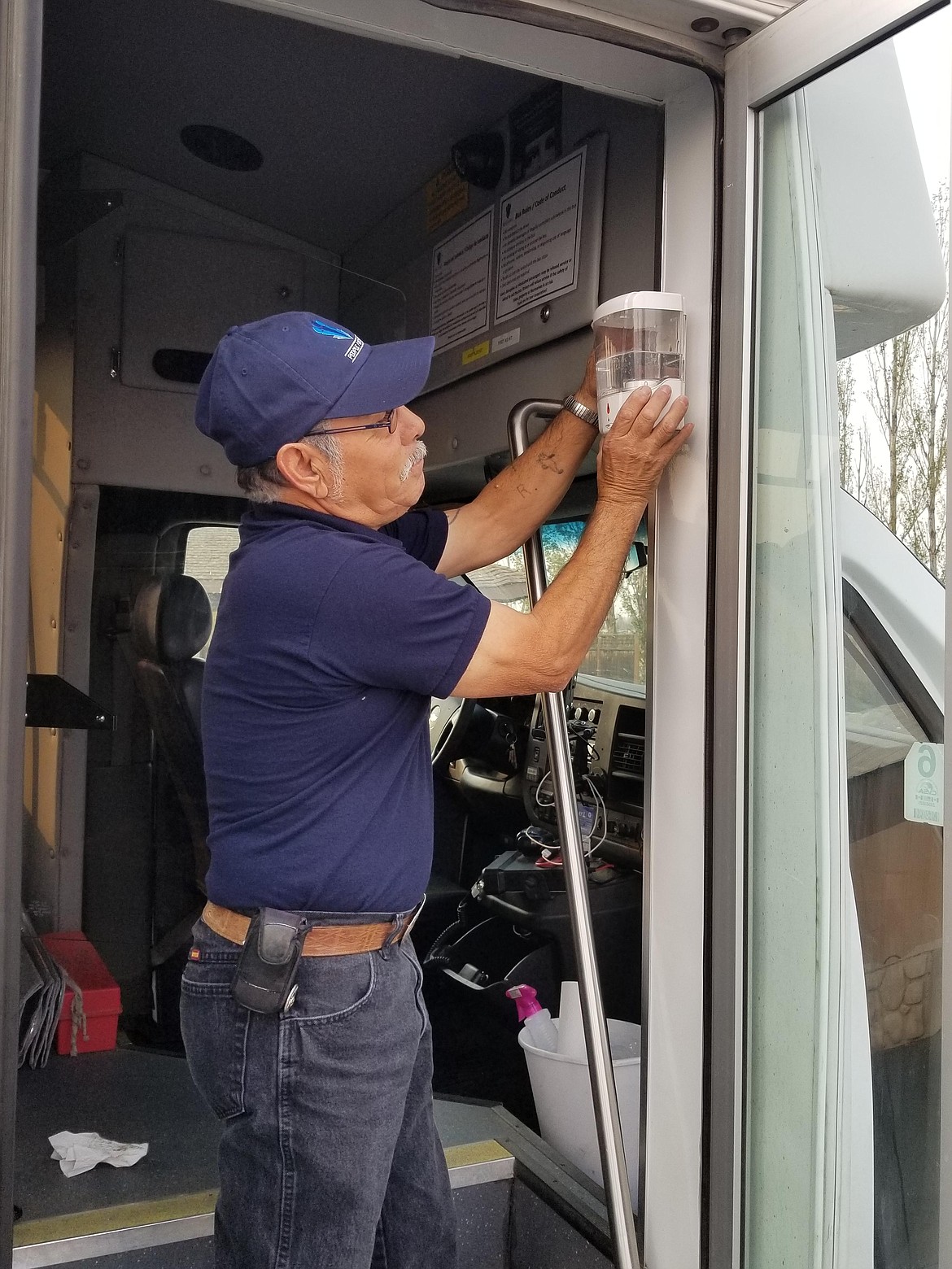 Ruben Balderas, a bus driver for People For People (PFP), installs a hand sanitizer dispenser in a PFP bus. The hand sanitizing stations were purchased with a grant through the Rotary Club of Moses Lake.
