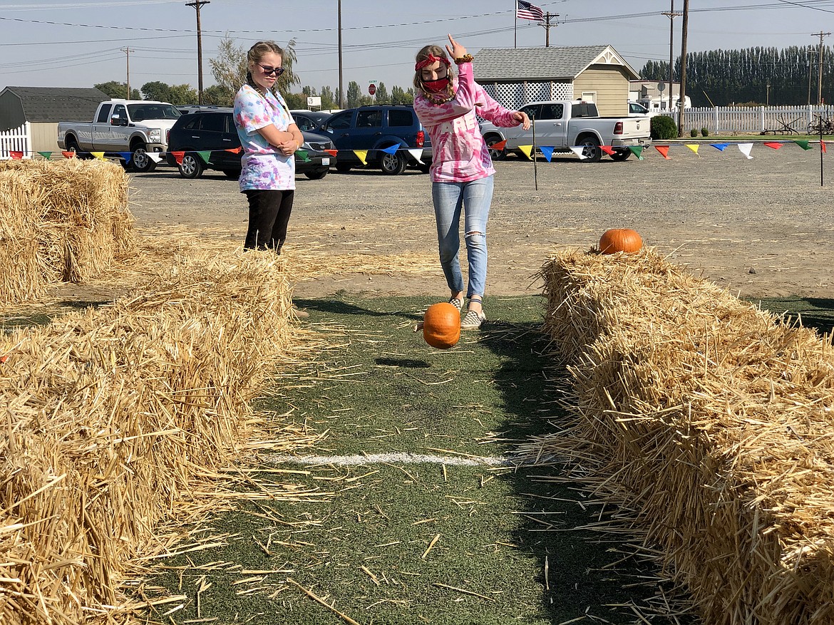 Kathryn Phillips, 15, tries her hand at pumpkin bowling while her cousin, 14-year-old Jaycee Freeman, looks on.