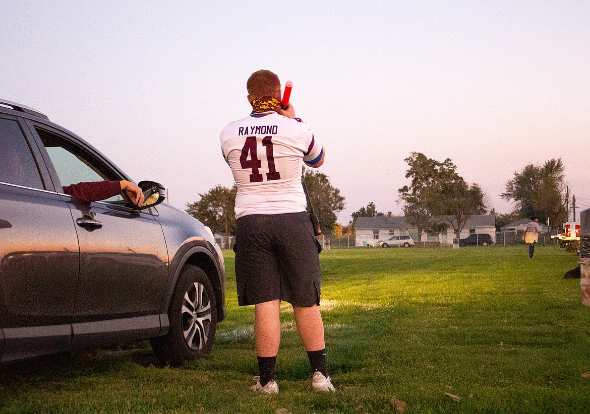 Moses Lake High School's Reise Raymond directs cars as they pull into Lions Field on Friday, Oct. 2, for the Friday Night Football Flashback event.