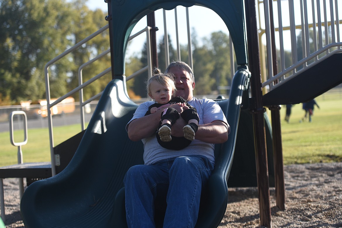 Jay Graham and granddaughter Everly Graham take an inaugural slide at the new Libby Elementary School playground. The playground was dedicated to Judy Graham, wife of Jay Graham, grandmother of Everly Graham and longtime Libby teacher who passed away in 2019.