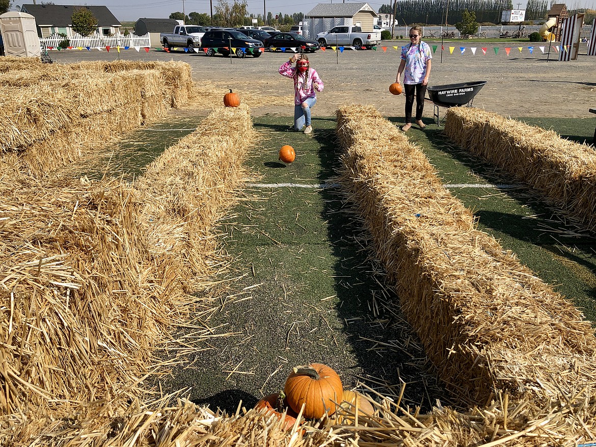Kathryn Phillips, 15, and her cousin Jaycey Freeman, 14, practice pumpkin bowling on Saturday on the opening day of County Cousins' Fall Festival.