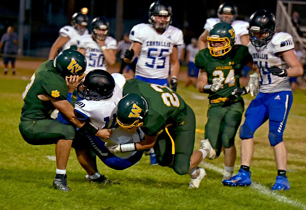 Whitefish's Ty Schwaiger sacks Corvallis quarterback Bryce Mayn with assist from his teammates during a game Friday night at home. (Whitney England/Whitefish Pilot)