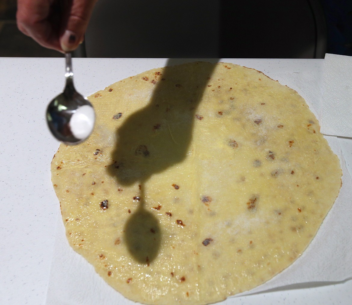 Sugar is added to a round of lefse before eating.