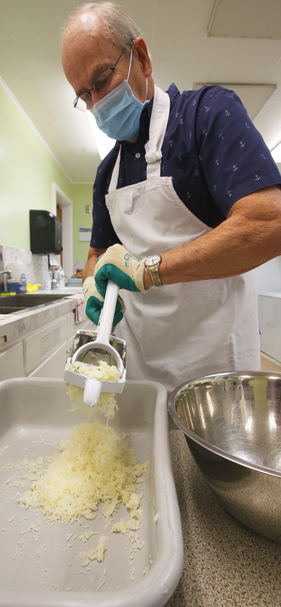 Paul Hunt uses a grater to turn the boiled, peeled potatoes into a rice form on Wednesday.