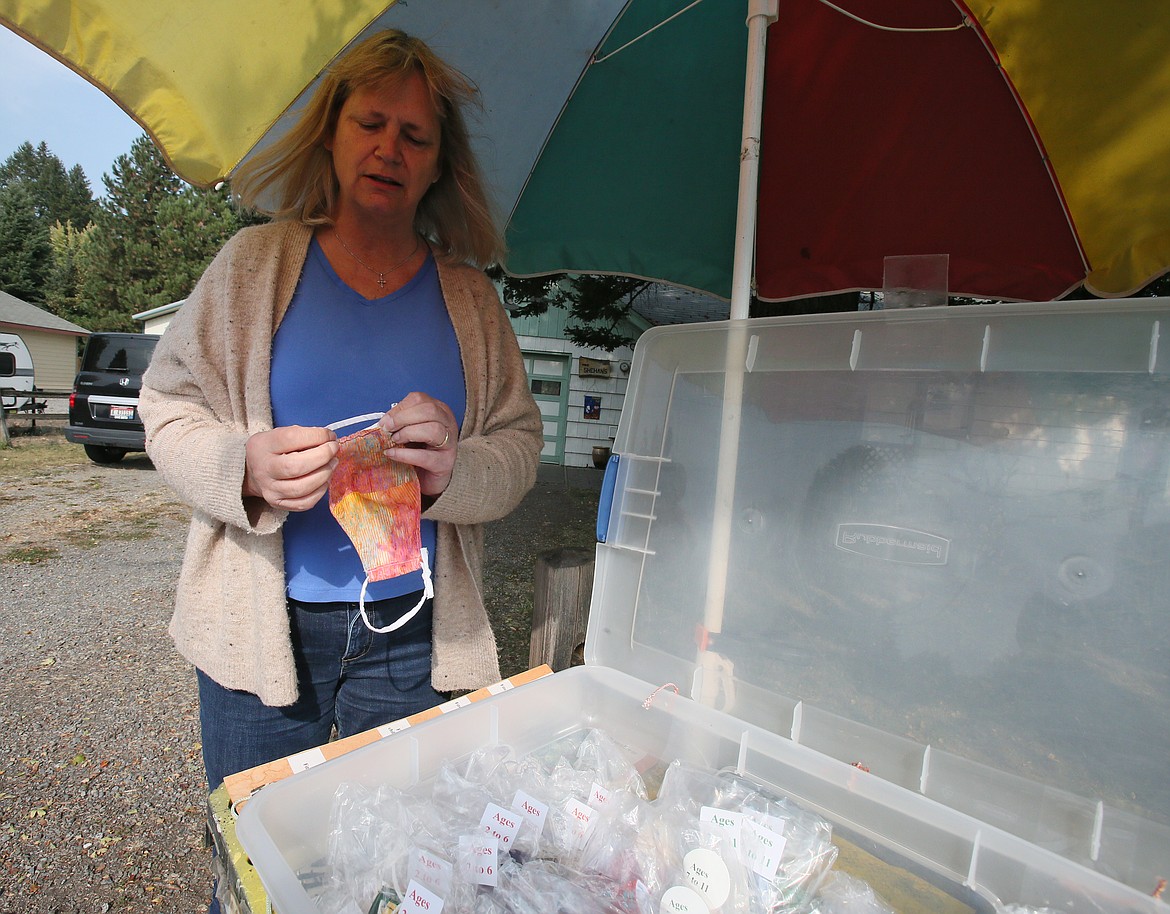 Ann Shehan, of Hayden, demonstrates how the loops tie on the fabric masks she makes and gives out for free during a visit to her Miles Avenue home on Thursday. Shehan leaves a container of masks at the end of her driveway to provide for those in need.