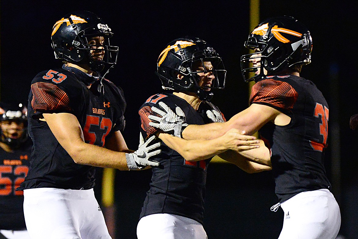 Flathead’s Luke Leech (53) and Dylan Zink (17) celebrate with Nolan White (35) after White’s interception in the first quarter against Butte at Legends Stadium on Friday. (Casey Kreider/Daily Inter Lake)
