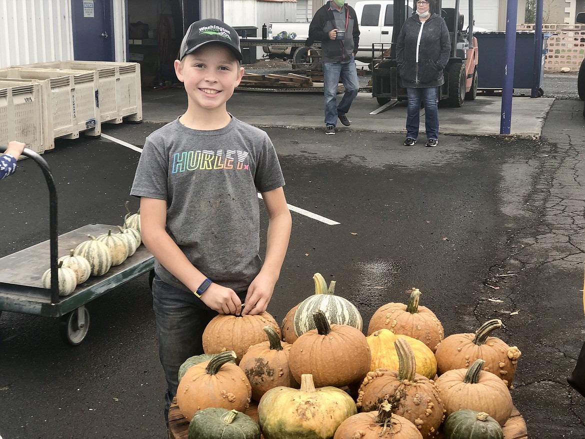 Carson Williamson, 10, with a stack of pumpkins at the Soroptomist pumpkin sale on Saturday, in between helping customers pick out and haul pumpkins. Williamson, whose father Eric grew the pumpkins and mother Hillary organized the sale, explained why he was helping bye saying, "I just like giving back to people and everything."