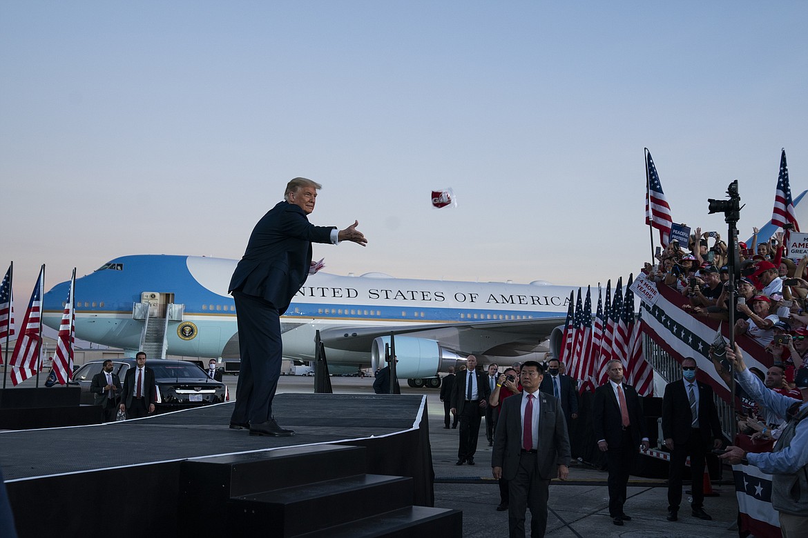 President Donald Trump tosses face masks into the crowd as he arrives for a campaign rally at Orlando Sanford International Airport, Monday, Oct. 12, 2020, in Sanford, Fla.