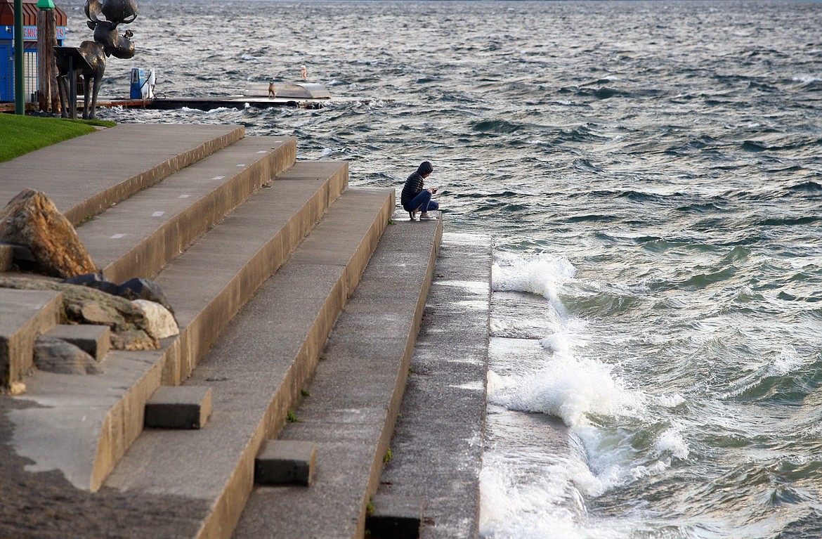 Waves crash against the stairs at Independence Point while a visitor watches on Tuesday afternoon.