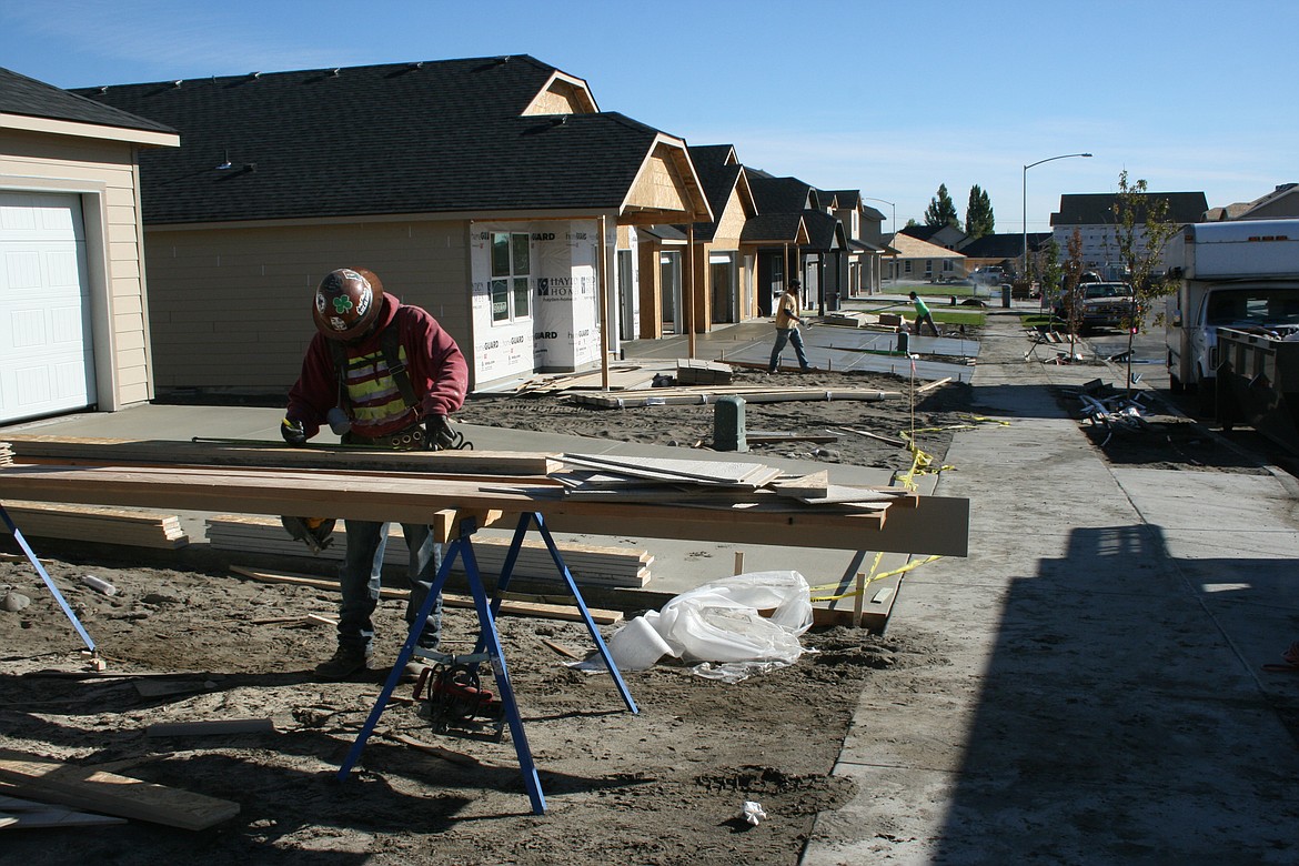 Construction workers swarm over a street of houses on a development near Moses Lake.