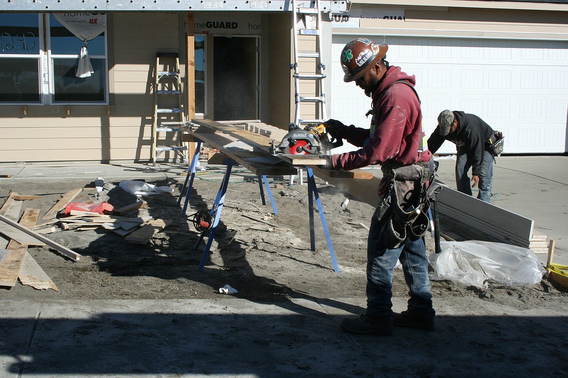 Gustavo Silva prepares trim for a house under construction in a development near Moses Lake.