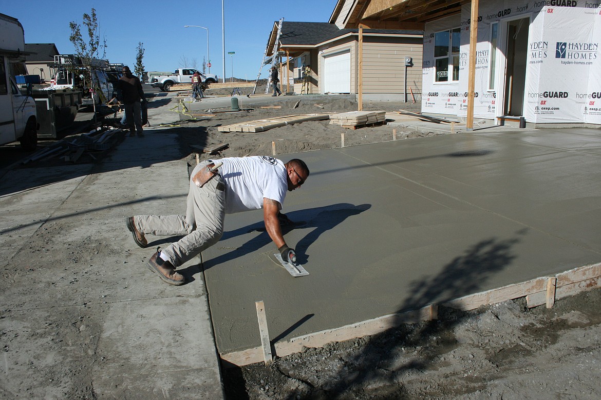 Javier Alvarado applies the finish coat to a driveway in a development near Moses Lake.