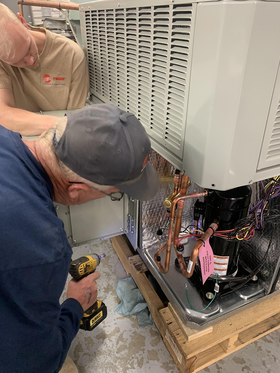 Stephen Stucky, left, and Dave Grant of Polhamus Heating & A/C Inc. work on a getting a package unit ready to install for a commercial building