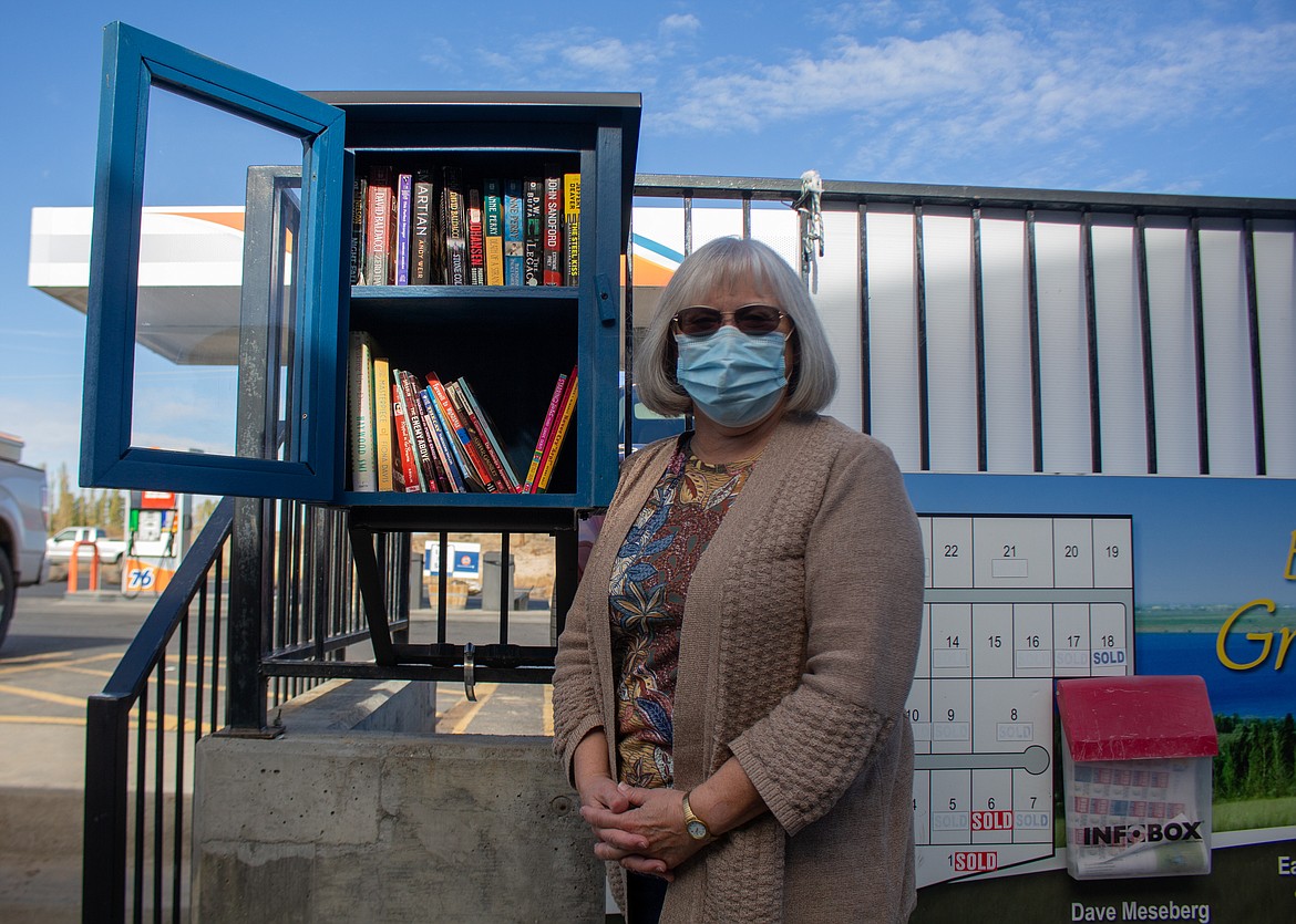 Susan Piercy, president of the Royal City Friends of the Library, stands beside the Little Free Library she helped get installed near Potholes General Store.