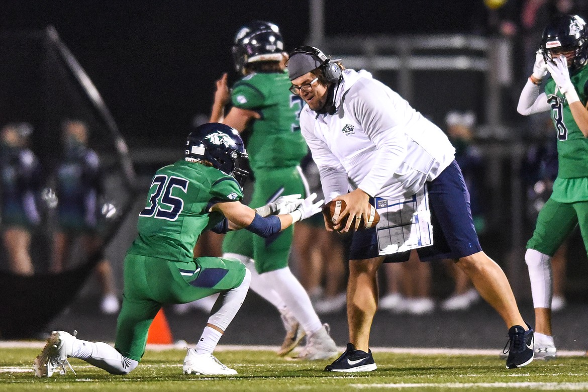 Glacier's Tyler Hausmann (35) hands over a football to assistant coach Jesse Rigler after Hausmann intercepted a pass in the second quarter against Flathead during crosstown football at Legends Stadium on Friday. (Casey Kreider/Daily Inter Lake)