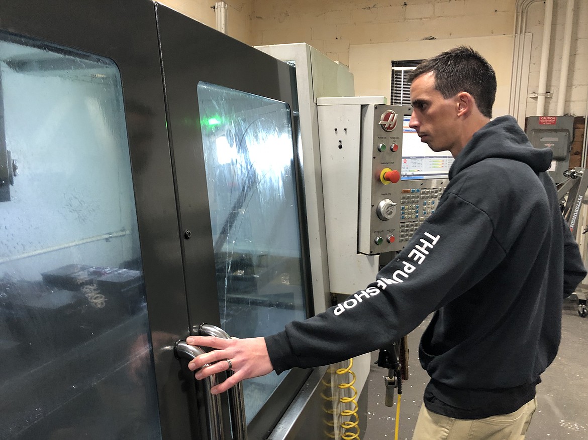 After quickly programming the computer numeric control (CNC) milling machine, Brandon Gervais watches as it starts to mill a roller wheel, a custom order for a customer.