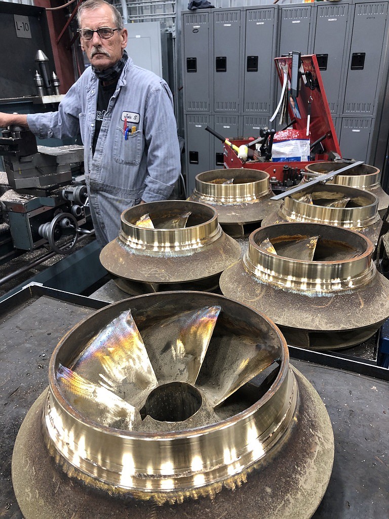 A machinist at Pasco Machine shows off several refurbished pump impellers.