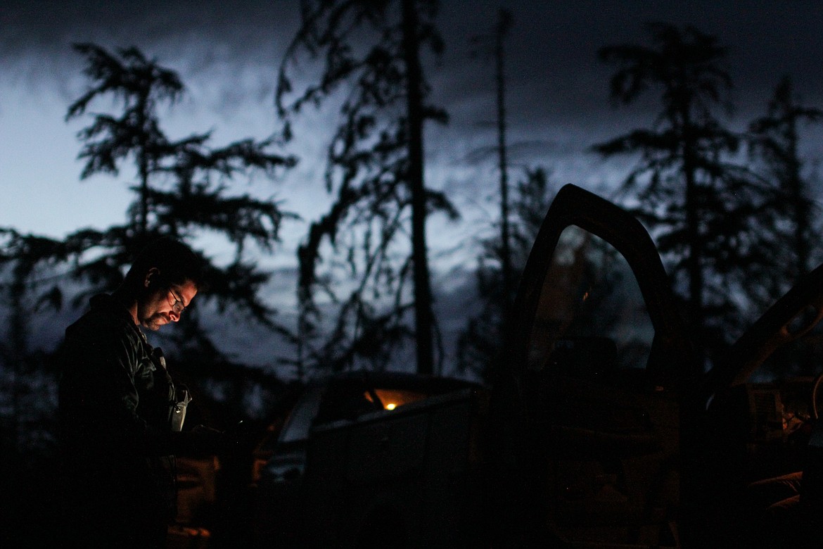 The light from a cellphone lights the face of a logger in the early morning hours.