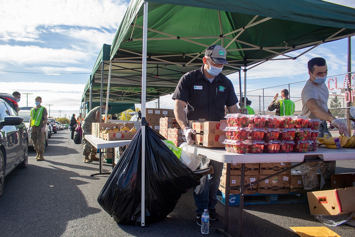 Alex Valdez, front left, with Second Harvest, and Washington Army National Guard member Mackenzie Shepherd, front right, compile together fruit items for distribution at the Second Harvest Mobile Market in Othello on Tuesday.