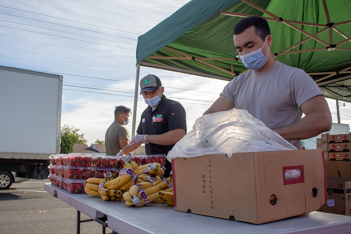 Alex Valdez with Second Harvest, left, and National Guard member Mackenzie Shepherd, right, compile together items to be distributed at the Second Harvest Mobile Market in Othello on Tuesday.