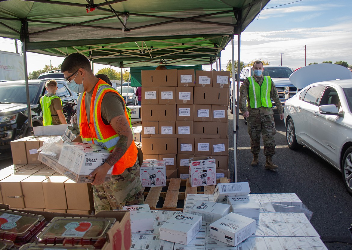 Jairzino Andrade, left, a member of the Washington Army National Guard, assists with getting items together during the Second Harvest Mobile Market food distribution in Othello on Tuesday.