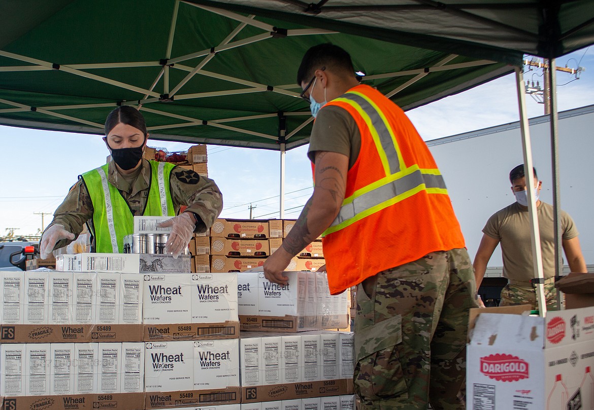 Trynity Mendez, left, and Jairzino Andrade gather items together as they get set for the next car to pull forward during the Second Harvest Mobile Market food distribution in Othello on Tuesday.