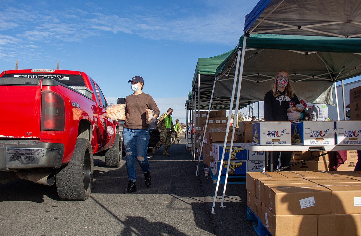 Volunteers, Abi Withers, left, and Rebekah McCort, right, help distribute items at the Second Harvest Mobile Market food distribution in Othello on Tuesday morning.