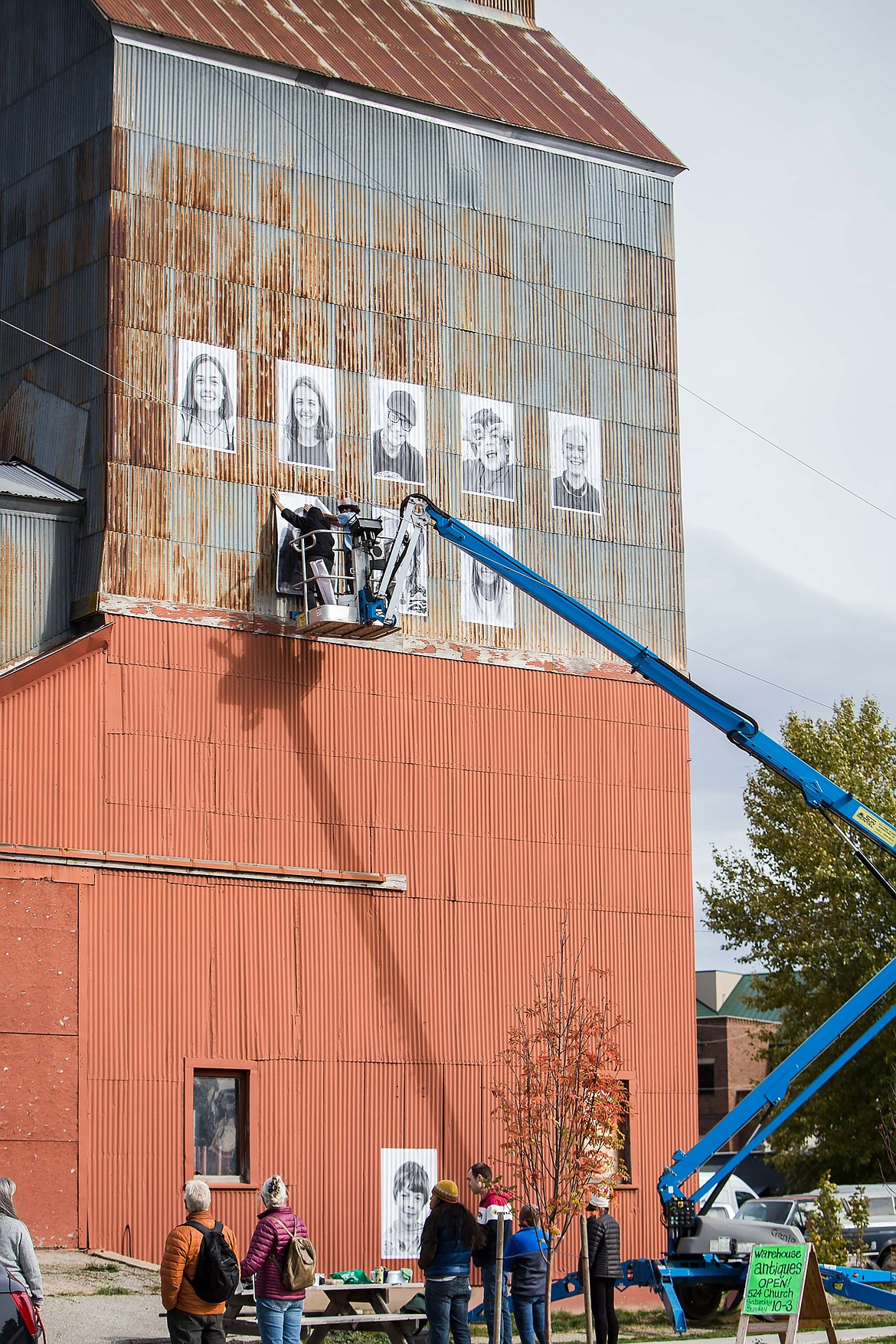 Crews work to install a temporary art project entitled the “Inside Out Project” — an effort to promote inclusivity and tolerance — on the corrugated tin granary building.