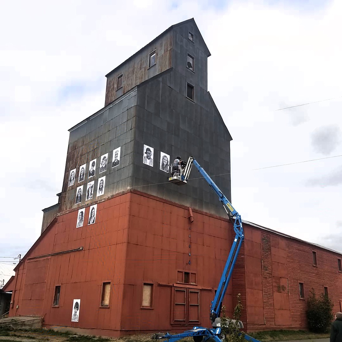 Crews work to install a temporary art project entitled the “Inside Out Project” — an effort to promote inclusivity and tolerance — on the corrugated tin granary building.