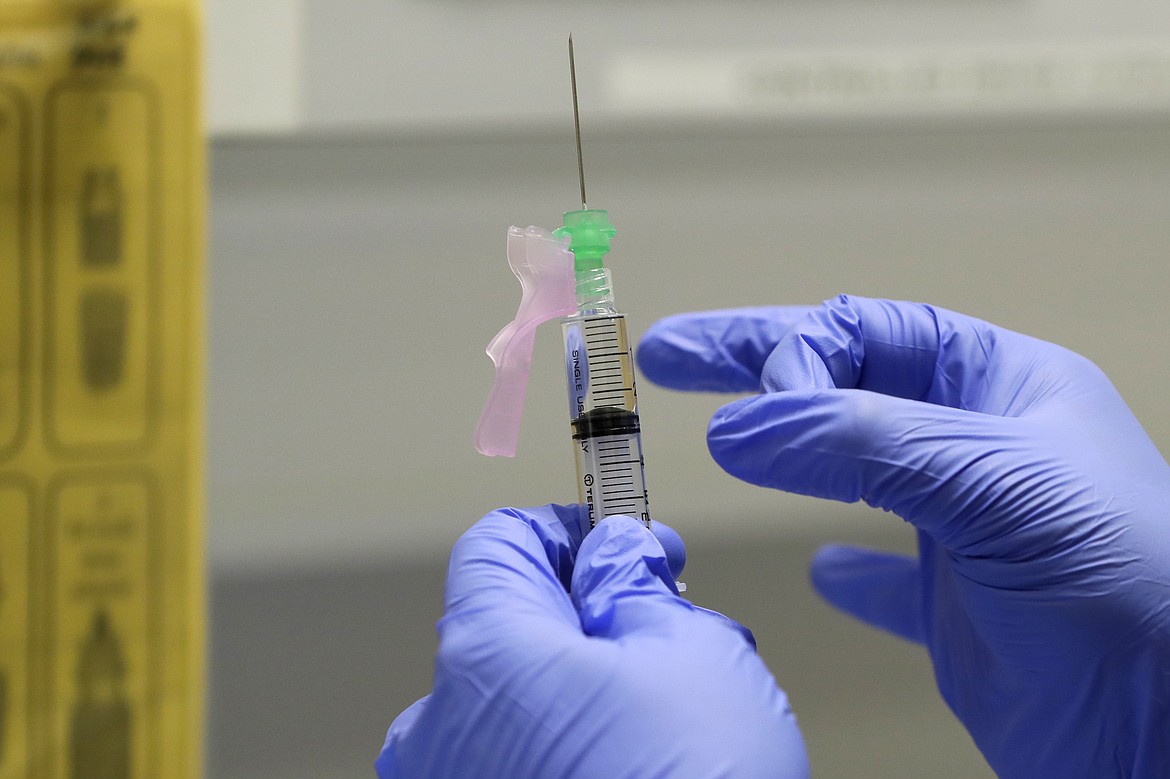 In this Wednesday, Aug. 5, 2020 file photo, senior Clinical Research Nurse Ajithkumar Sukumaran prepares the COVID-19 vaccine to administer to a volunteer, at a clinic in London. U.K. researchers said Tuesday Oct. 20, 2020, they are preparing to begin a controversial experiment that will infect healthy volunteers with the new coronavirus to study the disease in hopes of speeding up development of a vaccine.