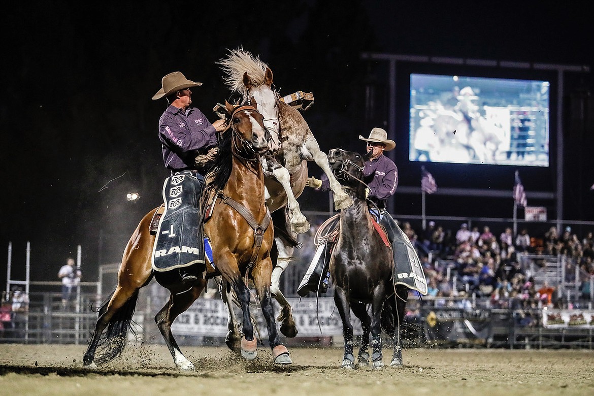 Pick-up men Cody Flitton and Ty Reeder work on uncinching Paint Me Ruby at a rodeo in Logan, Utah.