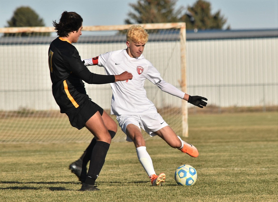 Sophomore defender Evan Dickinson looks to kick the ball past a Bishop Kelly defender on Friday.