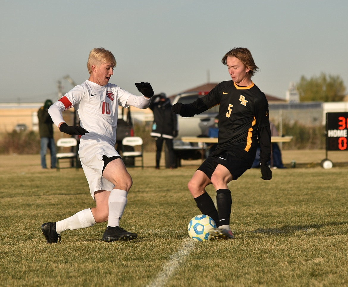 Senior forward Zander Moore challenges a Bishop Kelly player for possession of the ball during Friday's match.